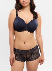 Woman wearing a navy blue lace bra and panties set on a white background