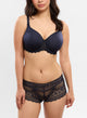 Woman wearing a navy blue lace bra and panties set on a white background