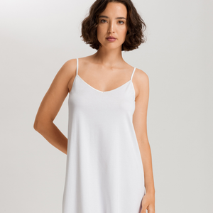 Woman wearing a white slip dress against a plain background