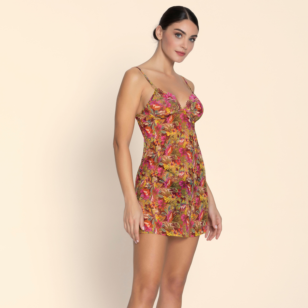 Woman wearing a colorful floral dress against a beige background