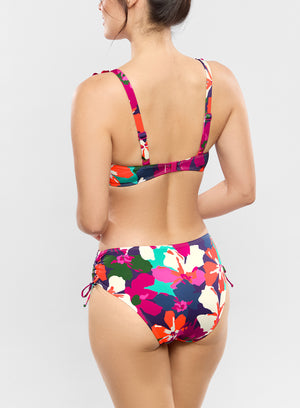Woman wearing a colorful floral bikini set on a light gray background