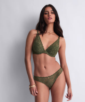 Woman wearing a green lace bra set against a plain background
