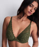 Woman wearing a green lace bralette against a plain background