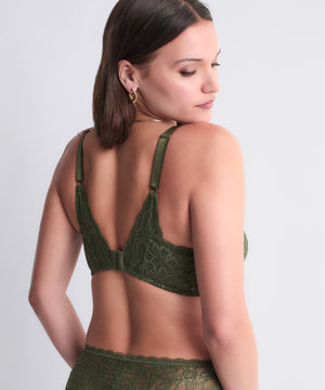 Woman wearing a green lace bra against a plain background