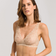 Woman wearing a beige lace bra against a plain background