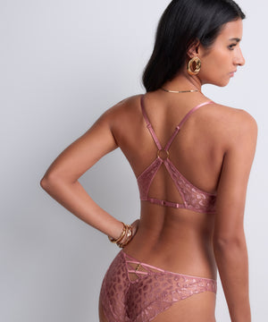 Woman wearing a pink lace lingerie set on a plain background