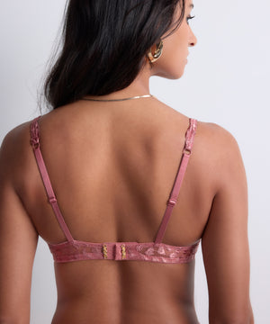 Woman wearing a pink bra on a plain background
