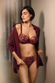 Woman wearing a burgundy lace lingerie set with a matching shirt.