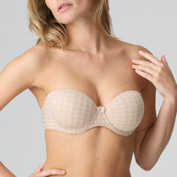 Beige strapless bra worn by a model on a plain background