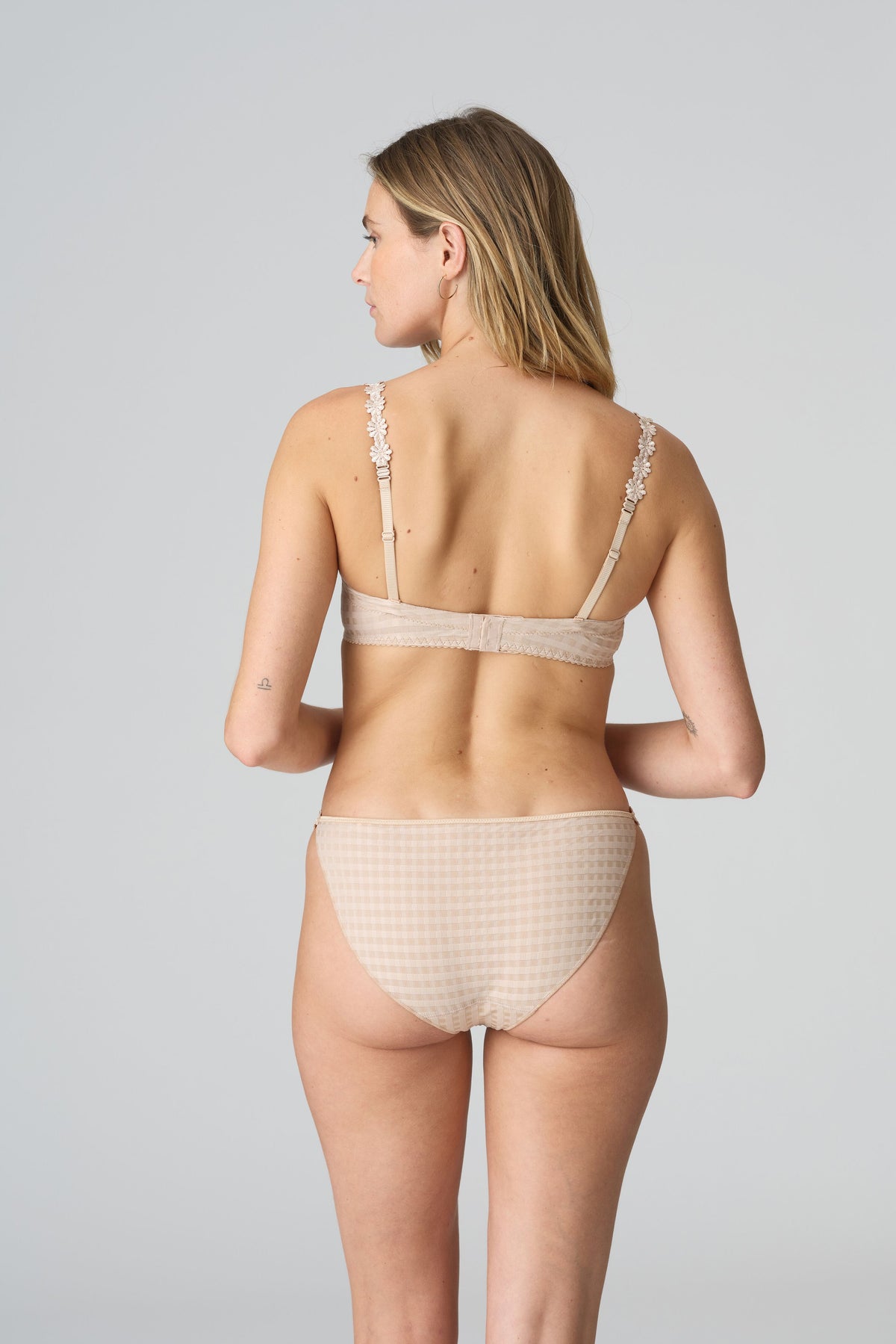 Woman wearing a beige bikini set on a gray background