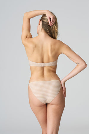 Woman wearing beige lingerie against a plain background