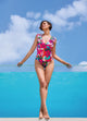 Woman in a colorful swimsuit standing by a pool with a blue sky background