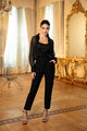 Woman in a black outfit standing in an elegant room with gold-framed mirror and curtains.