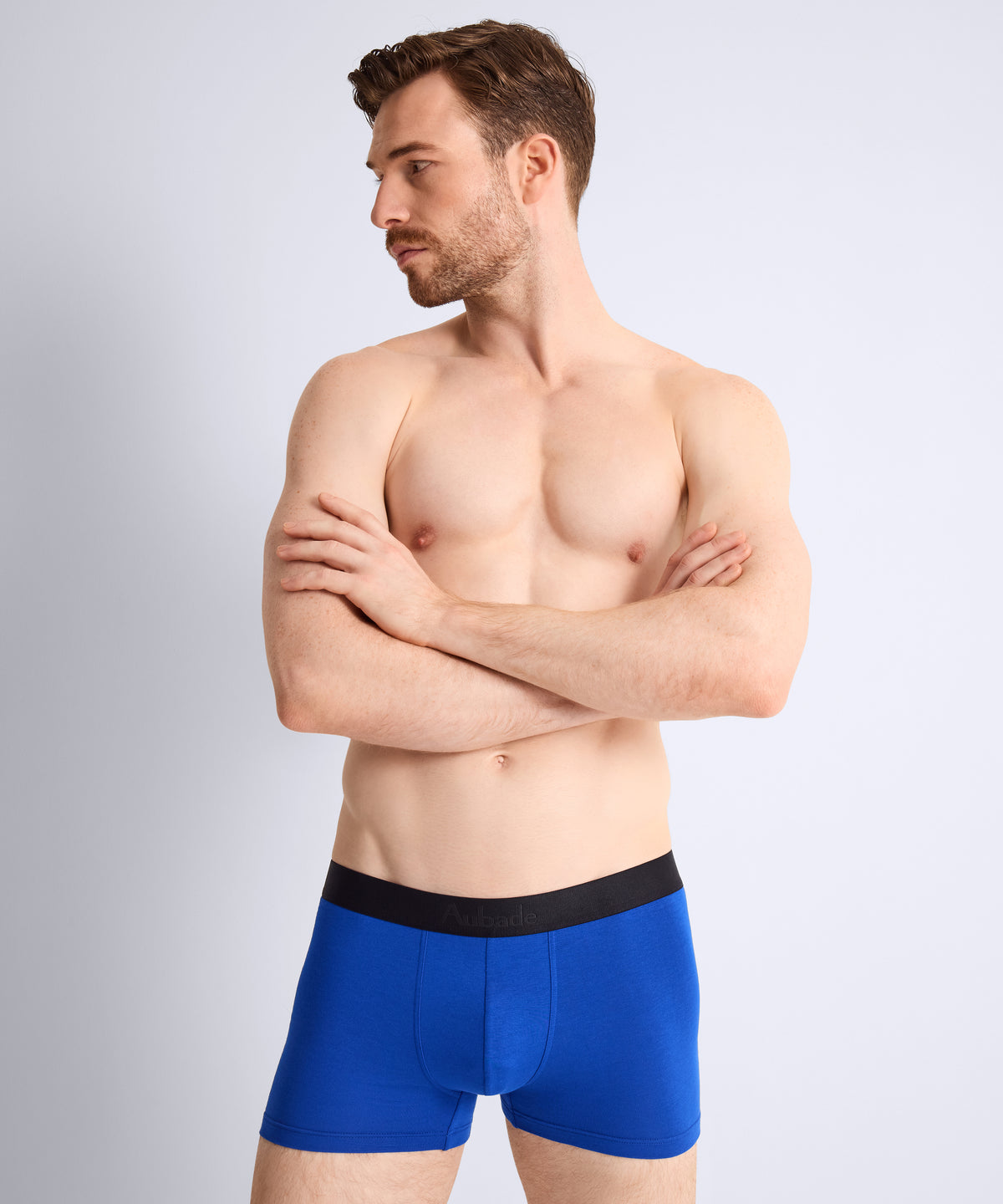 Man wearing blue boxer briefs with a plain background