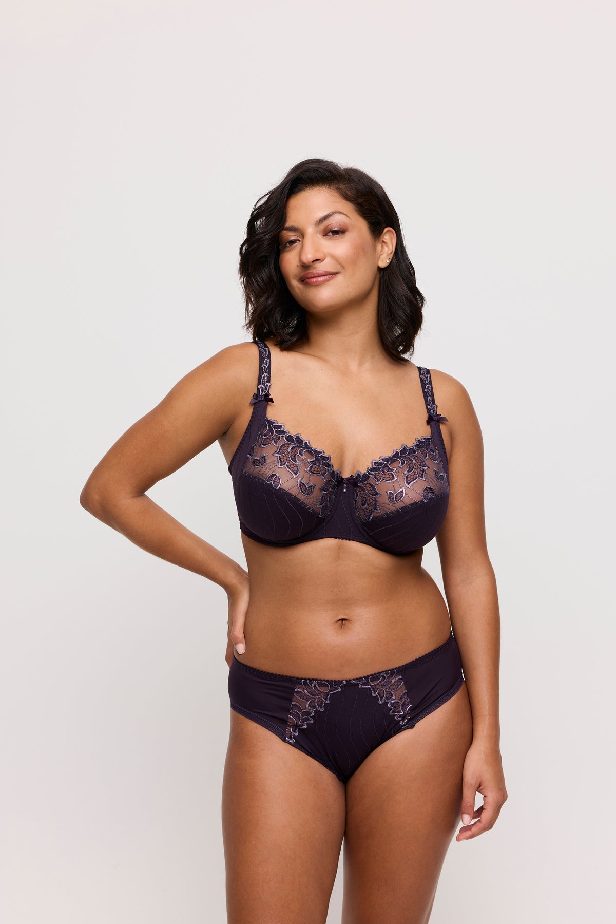 Woman wearing a navy blue lace lingerie set on a white background