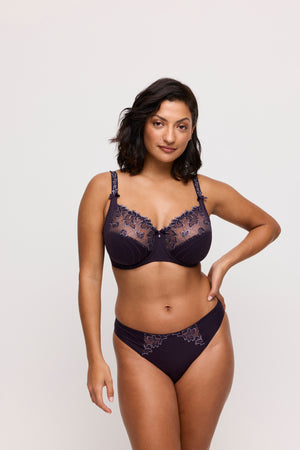 Woman wearing a dark blue lace lingerie set on a light gray background