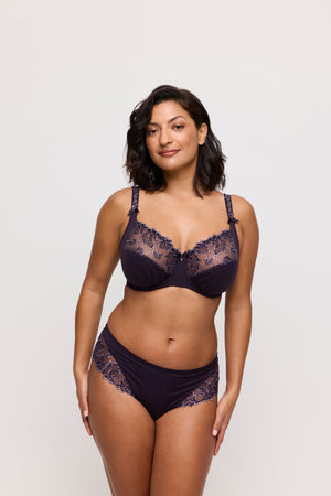 Woman wearing a dark lace lingerie set on a plain background