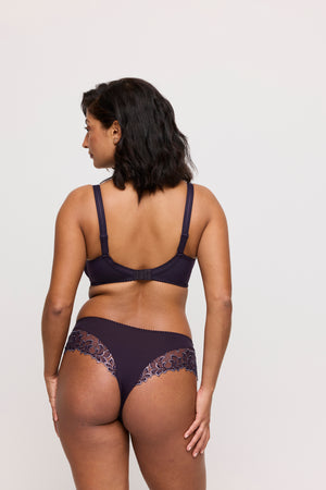 Woman wearing a dark purple lingerie set on a plain background
